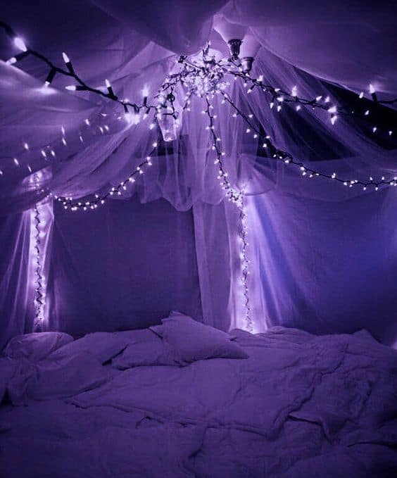 a canopy bed with fairy lights